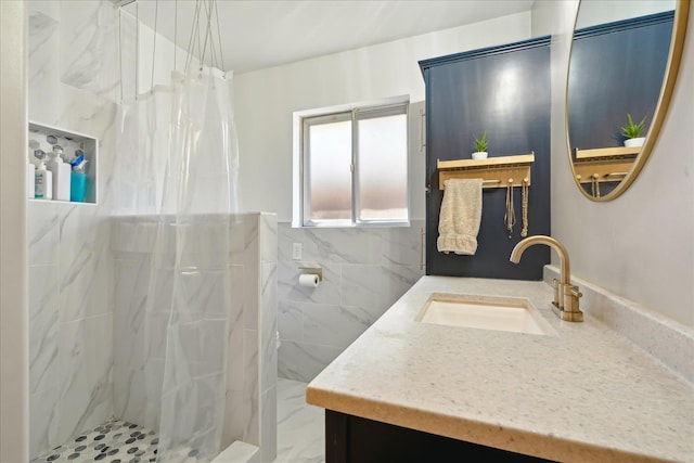 bathroom featuring marble finish floor, a marble finish shower, vanity, and tile walls