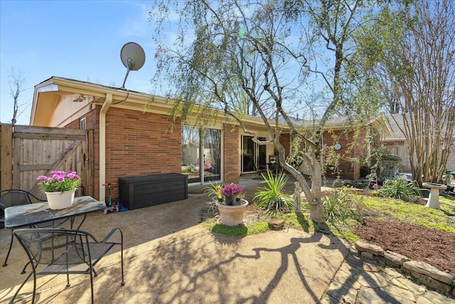 rear view of property featuring fence, a patio, and brick siding