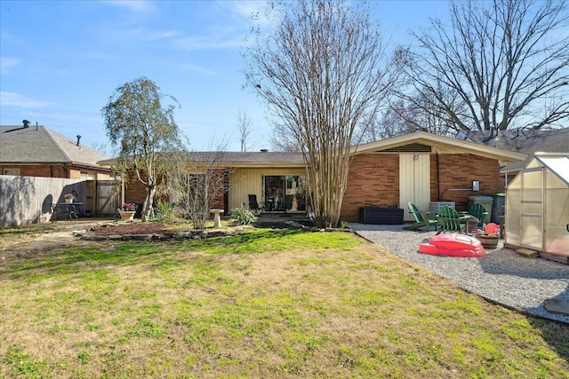 back of house featuring an outbuilding, a yard, a greenhouse, and fence