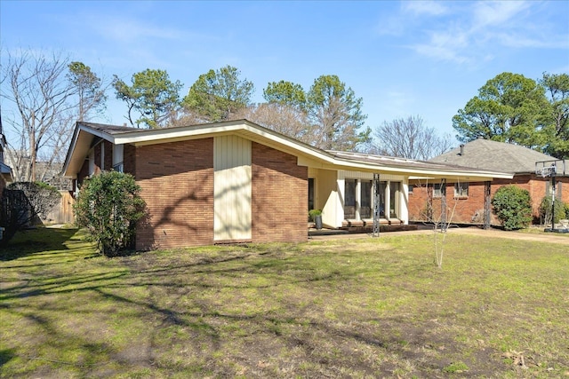 rear view of property with a yard and brick siding