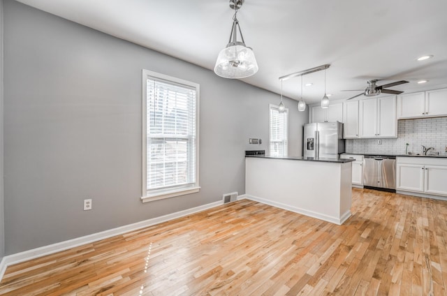 kitchen featuring stainless steel appliances, visible vents, white cabinetry, backsplash, and dark countertops