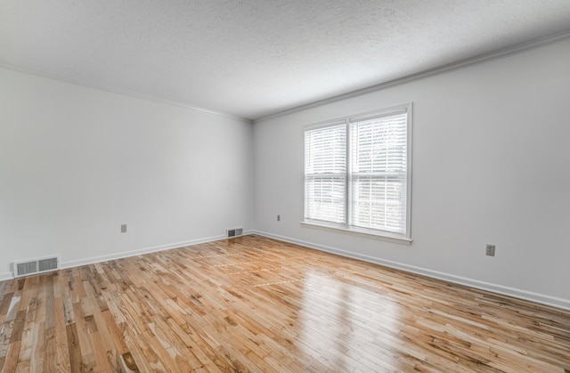 empty room featuring ornamental molding, light wood-type flooring, and visible vents