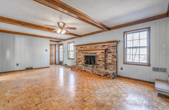 unfurnished living room featuring a wealth of natural light, baseboards, visible vents, and a textured ceiling