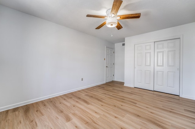 unfurnished bedroom featuring light wood-type flooring, a ceiling fan, baseboards, and a closet