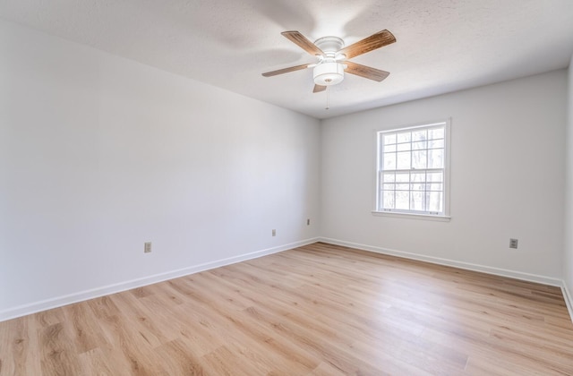 empty room with light wood finished floors, a ceiling fan, and baseboards