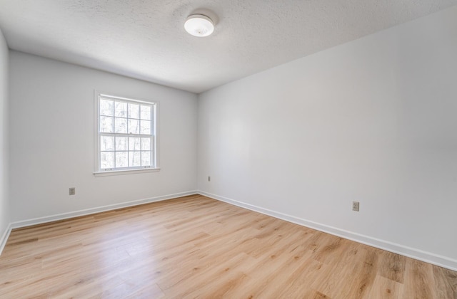 empty room with a textured ceiling, baseboards, and wood finished floors