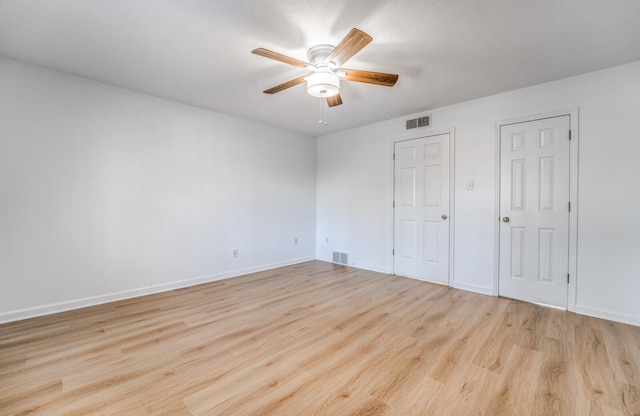 unfurnished bedroom featuring a ceiling fan, baseboards, visible vents, and wood finished floors