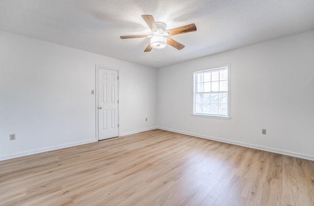 empty room with a ceiling fan, light wood-style flooring, and baseboards