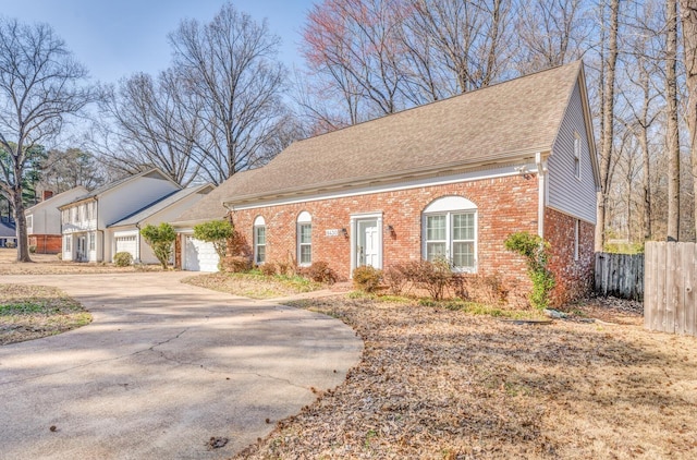 view of front of property featuring an attached garage, brick siding, a shingled roof, fence, and concrete driveway