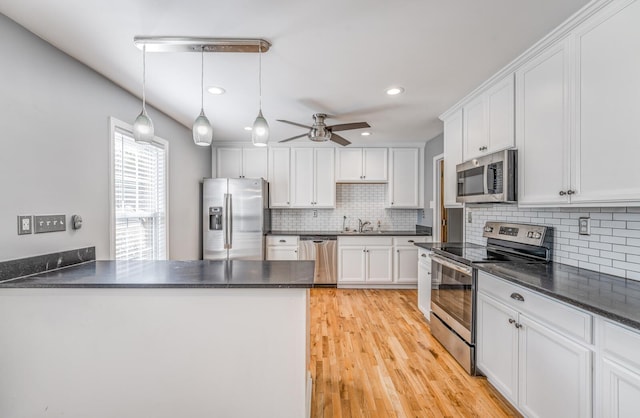 kitchen featuring stainless steel appliances, white cabinets, a sink, and a peninsula