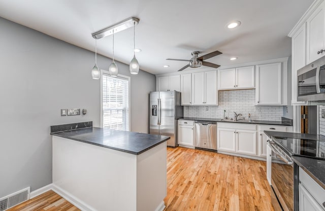 kitchen featuring stainless steel appliances, dark countertops, visible vents, and white cabinetry