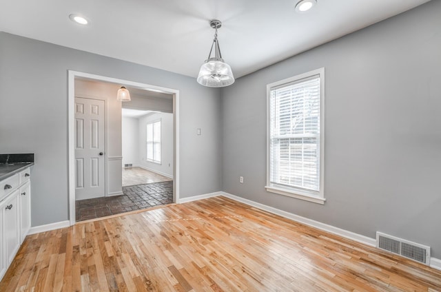 unfurnished dining area with light wood finished floors, baseboards, visible vents, and recessed lighting