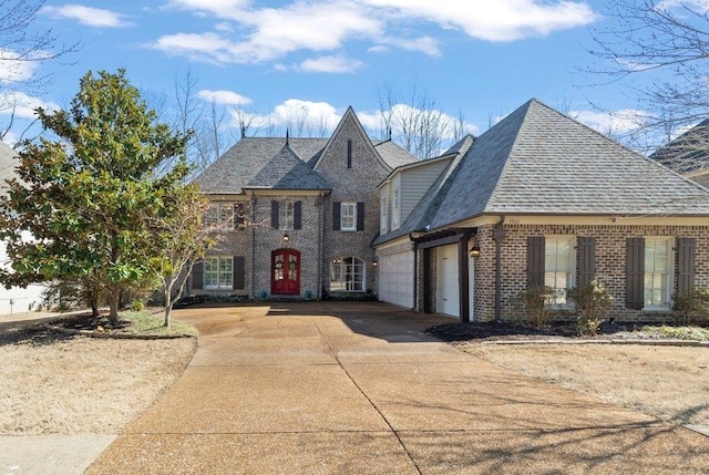 view of front facade featuring an attached garage, driveway, roof with shingles, and brick siding