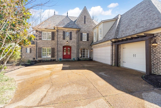 view of front of property with a garage, driveway, brick siding, and roof with shingles