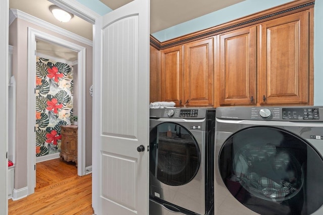 washroom featuring crown molding, light wood-type flooring, cabinet space, and washer and dryer