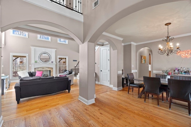 interior space featuring visible vents, arched walkways, light wood-style flooring, a premium fireplace, and ornamental molding