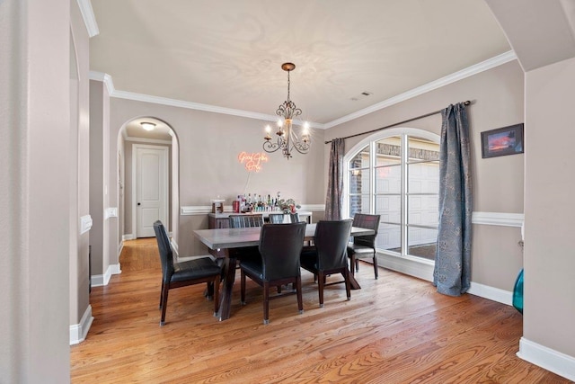 dining space with arched walkways, visible vents, light wood-style flooring, and baseboards