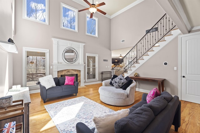 living area with ornamental molding, plenty of natural light, a fireplace, and wood finished floors