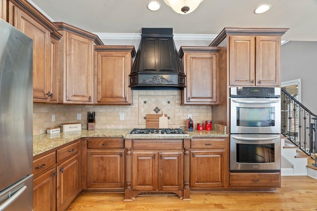 kitchen featuring brown cabinets, premium range hood, and stainless steel appliances