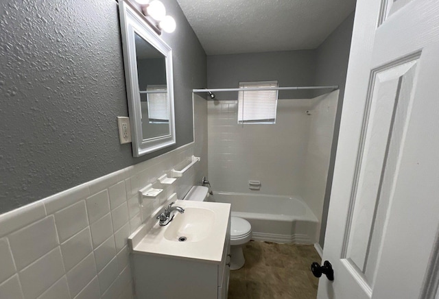 full bathroom featuring tile walls, shower / bath combination, toilet, a textured ceiling, and vanity