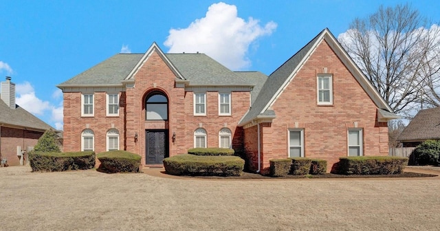 view of front of house with a shingled roof and brick siding