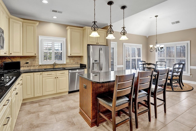 kitchen featuring stainless steel appliances, a breakfast bar area, a sink, and cream cabinets