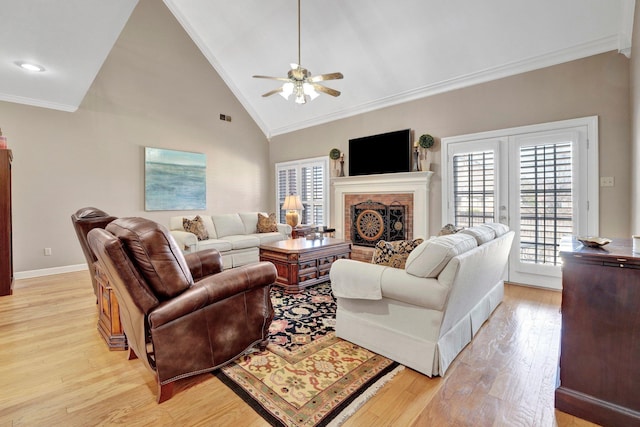 living room with a fireplace, visible vents, ornamental molding, light wood-style floors, and baseboards