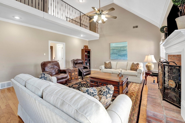 living room with light wood-type flooring, ornamental molding, a brick fireplace, and visible vents