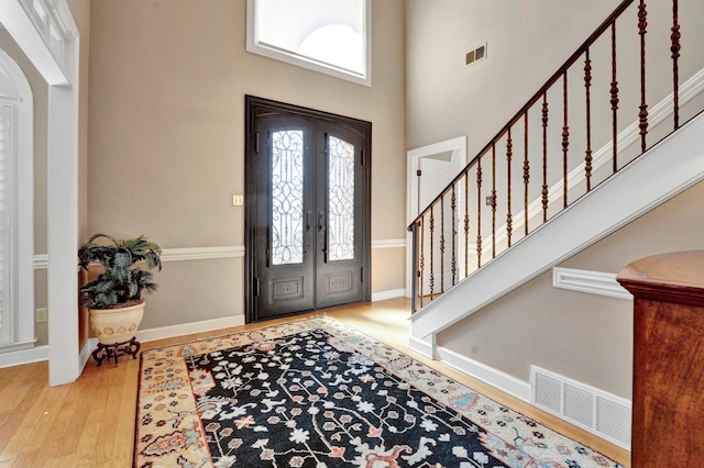 entryway with stairs, french doors, wood finished floors, and visible vents