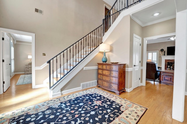 stairs with baseboards, crown molding, visible vents, and wood finished floors