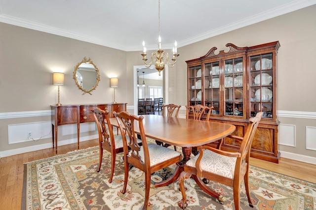 dining space with a chandelier, crown molding, and light wood-style floors