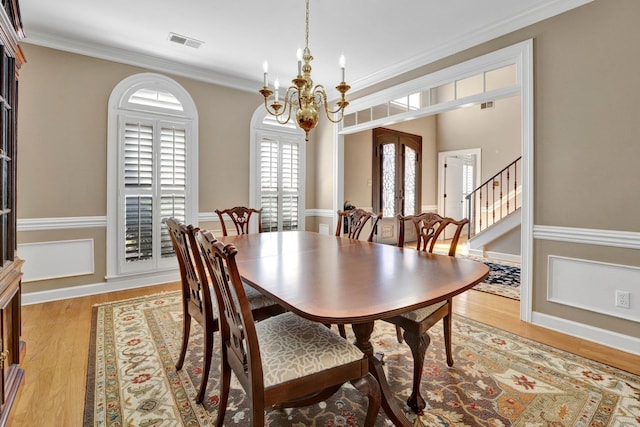 dining room featuring light wood-type flooring, visible vents, ornamental molding, and a notable chandelier