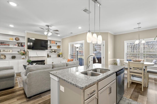 kitchen featuring dark wood-style flooring, a tiled fireplace, stainless steel dishwasher, open floor plan, and a sink