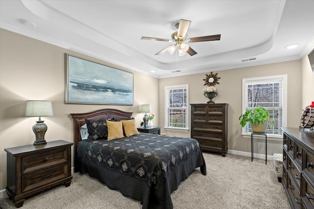 bedroom with baseboards, visible vents, light colored carpet, ornamental molding, and a tray ceiling