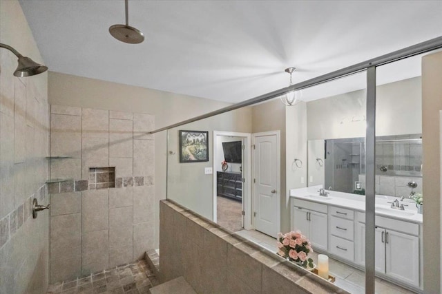 full bath featuring a tile shower, a sink, and double vanity