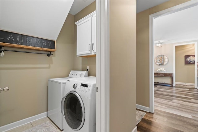 washroom featuring separate washer and dryer, light wood-style floors, cabinet space, and baseboards