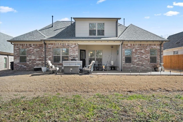 back of house with brick siding, a shingled roof, outdoor lounge area, a patio area, and fence