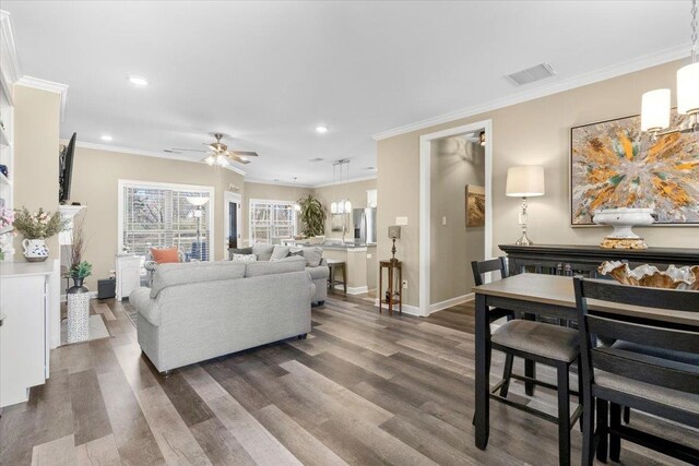 living area featuring baseboards, visible vents, ornamental molding, dark wood-type flooring, and recessed lighting