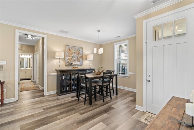 dining area featuring baseboards, visible vents, wood finished floors, and ornamental molding