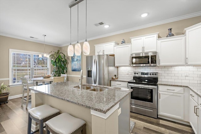 kitchen featuring crown molding, tasteful backsplash, visible vents, appliances with stainless steel finishes, and a sink