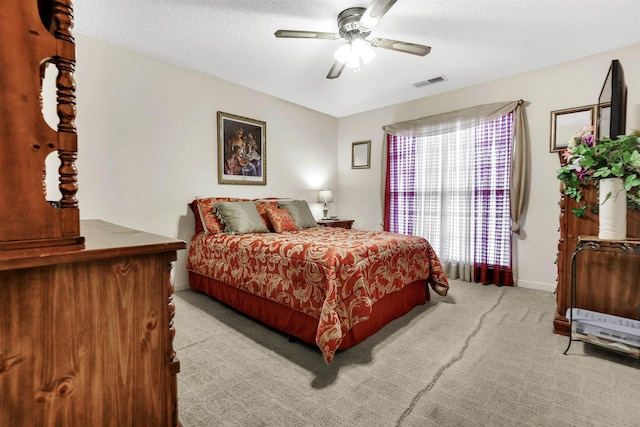 carpeted bedroom featuring a textured ceiling, ceiling fan, visible vents, and baseboards