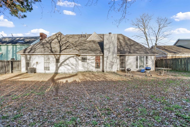 rear view of house with a fenced backyard, a chimney, cooling unit, and a patio