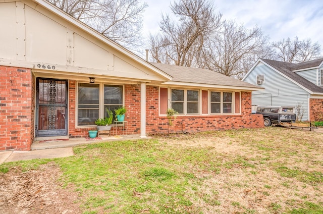 exterior space with brick siding and a front yard