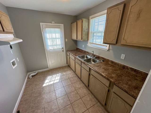 kitchen featuring dark countertops, a sink, baseboards, and light tile patterned floors