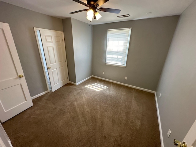 unfurnished bedroom featuring carpet floors, a ceiling fan, visible vents, and baseboards