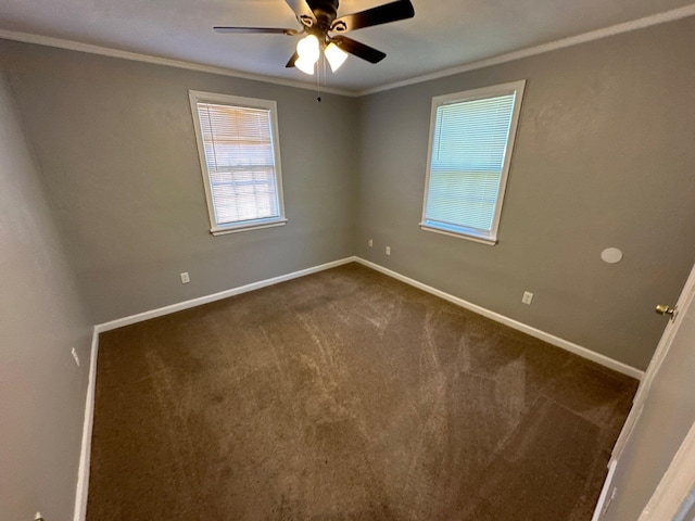 empty room with ornamental molding, dark colored carpet, baseboards, and a ceiling fan