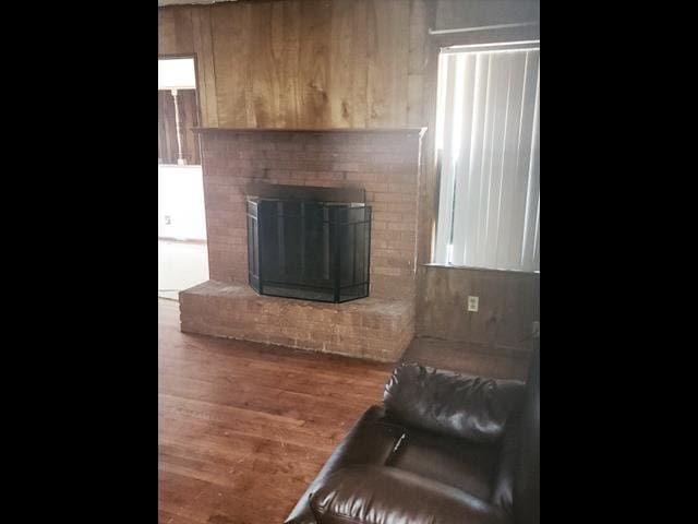 interior space with a brick fireplace and wood finished floors