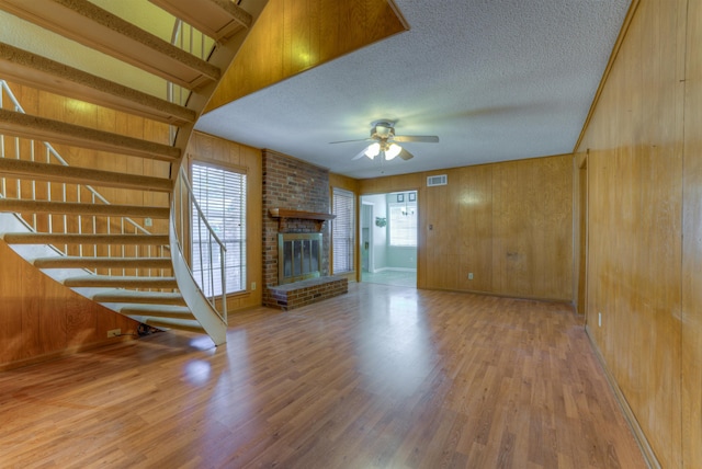 unfurnished living room featuring visible vents, plenty of natural light, a textured ceiling, and wood finished floors