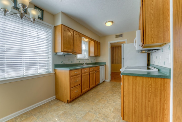 kitchen with white appliances, visible vents, baseboards, and a sink