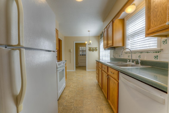 kitchen featuring white appliances, a sink, backsplash, and an inviting chandelier